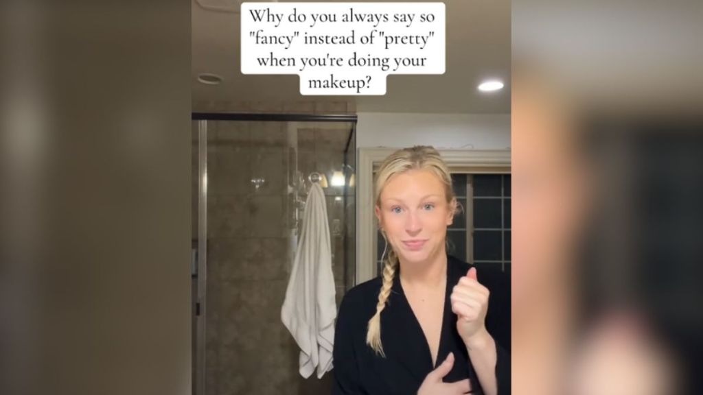 A blonde woman in a black bathrobe standing in the bathroom.