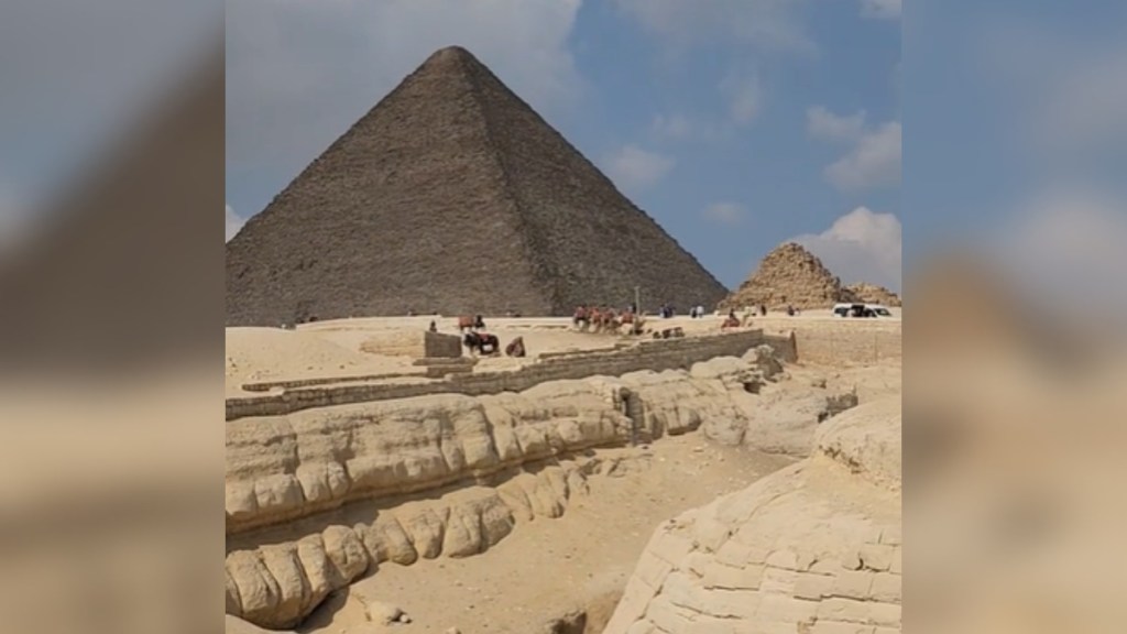 Distant view of the pyramids in Egypt, bright blue sky with white fluffy clouds behind them