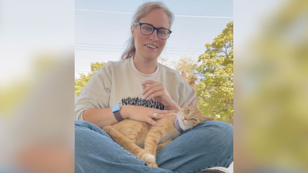 A woman sitting on the floor with a cat in her lap.