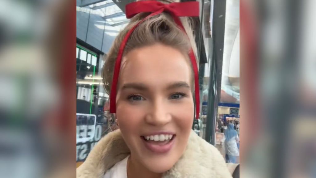 A blonde woman with a red ribbon on her head.