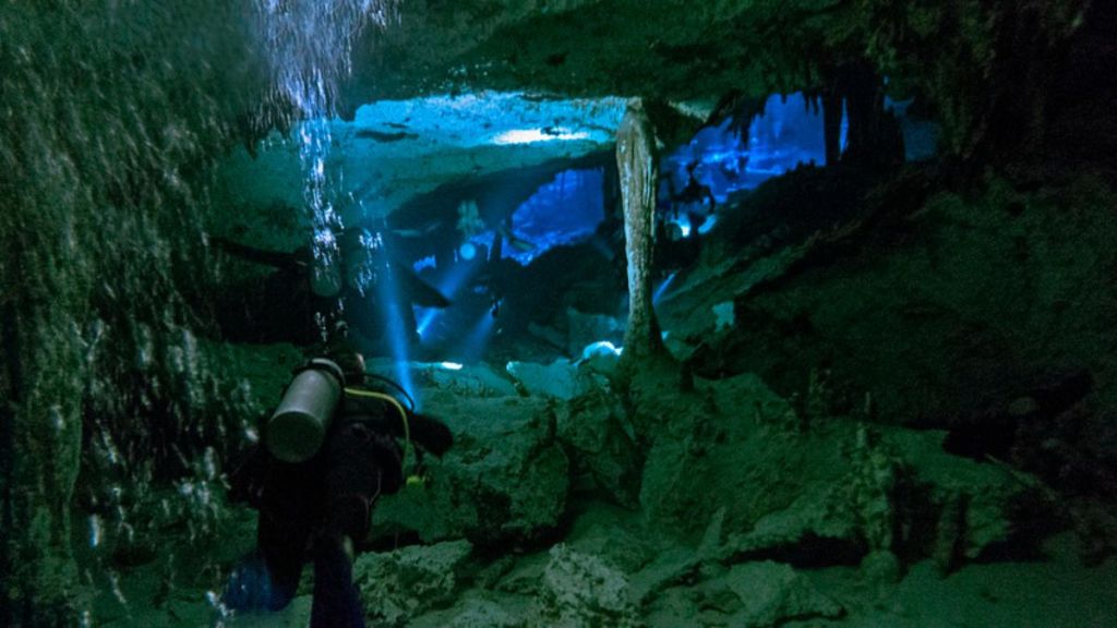 Image shows divers exploring an underwater cabe system.