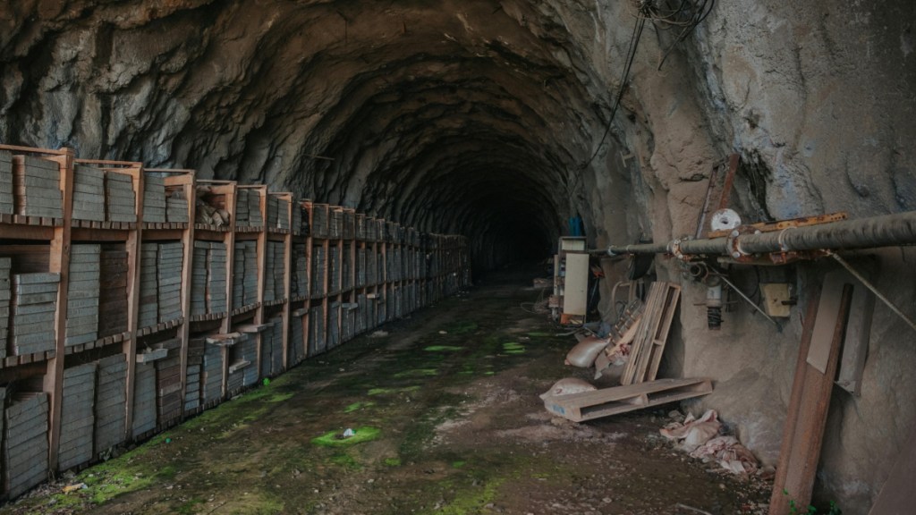 View inside a dark, spooky abandoned mine. Various equipment and items have been left behind.