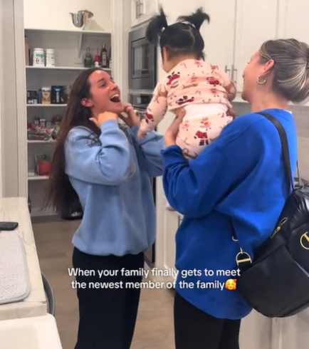 A woman having an excited reaction to meeting her relative's adopted baby girl.