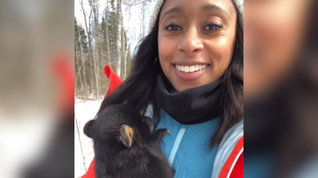 A woman holding a bear cub in her arms.