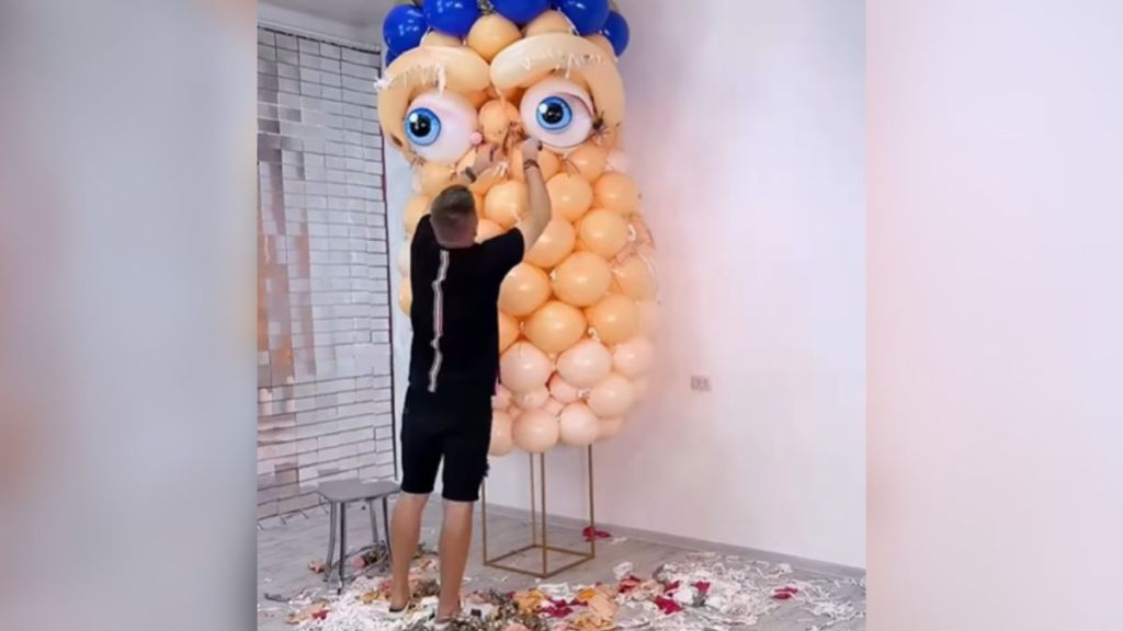 A man creating an art display out of balloons.