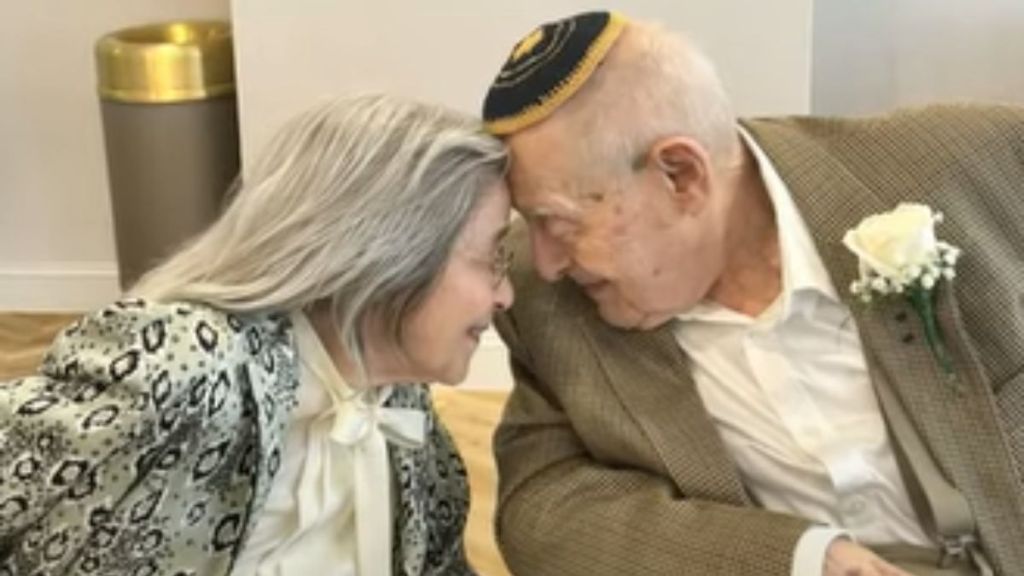 An elderly couple touching their foreheads together in a romantic moment.