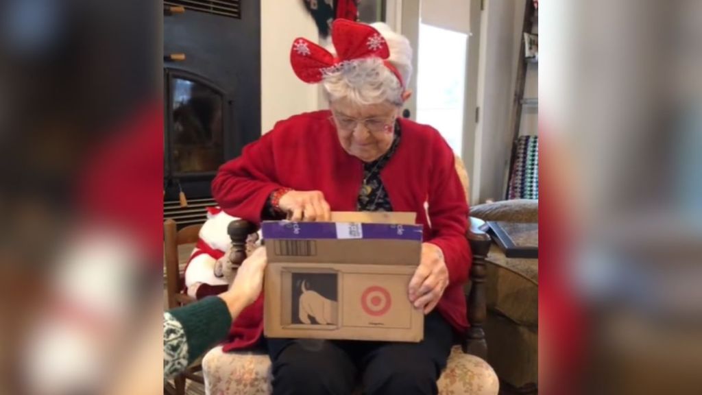 An elderly woman opening a Christmas present.
