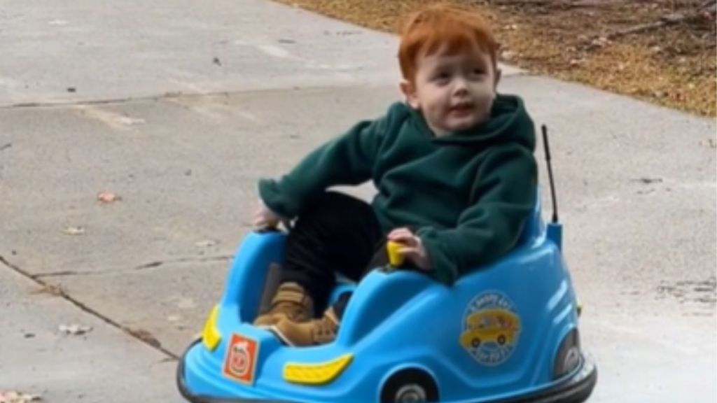 A little boy riding around in a blue toy car.
