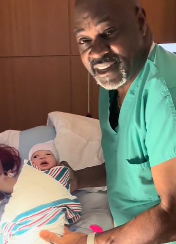 A doctor holding a newborn baby in his arms.
