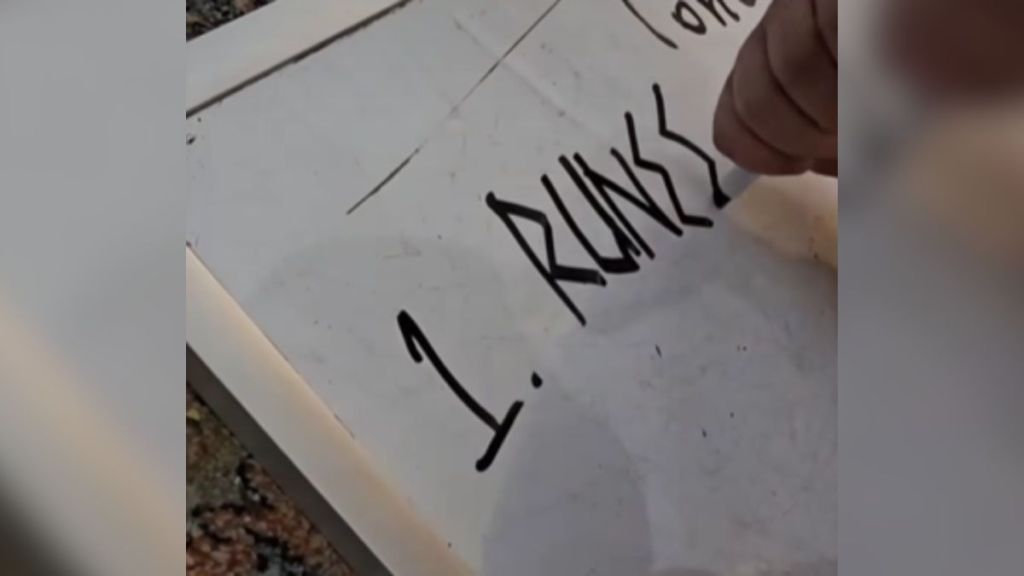 A hand writing the first entry in a list of different font styles.