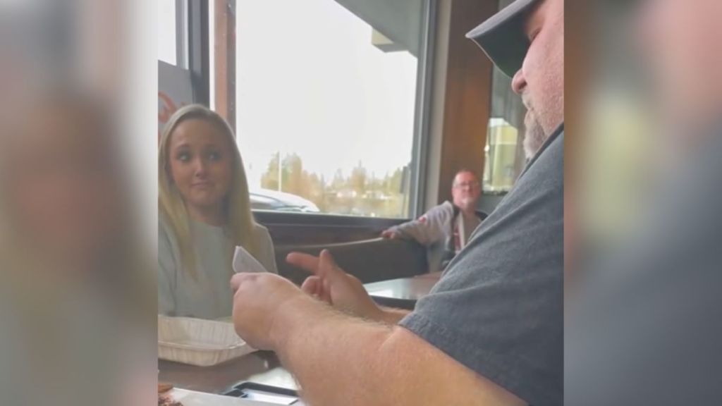 A man presenting a waitress at a restaurant with a gift.