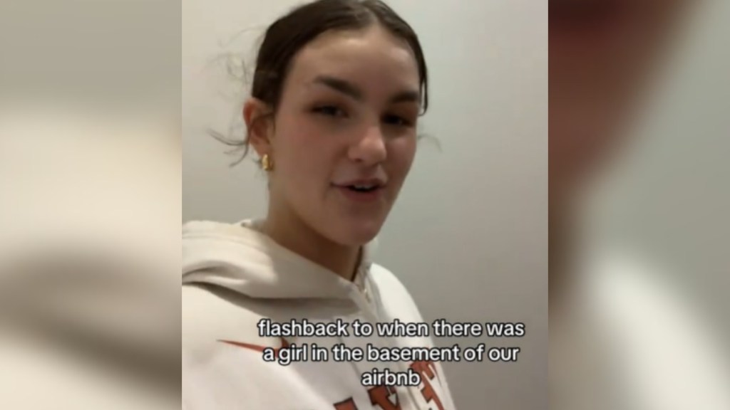 A woman smiles as she talks to the camera. Text on the image reads: Flashback to when there was a girl in the basement of our Airbnb