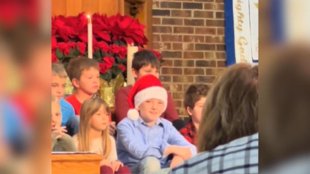 A group of children sitting at the front of a church during a Christmas performance.