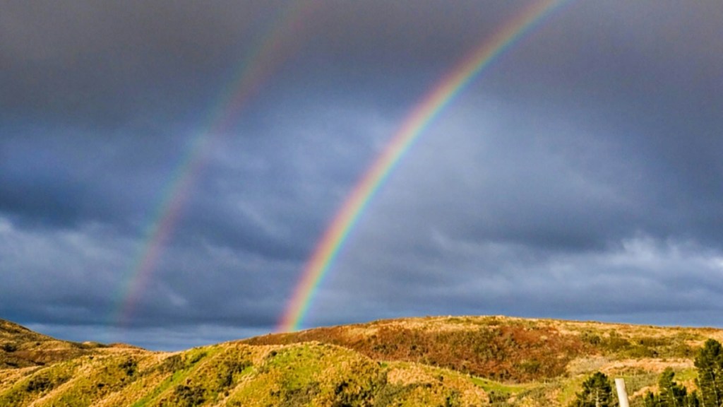 Distant view of a vibrant double rainbow over a mountainous area