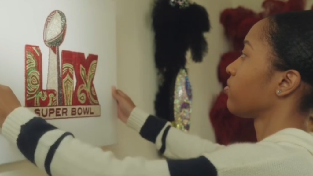 Side view of a woman as she places a canvas of the Super Bowl logo she created on a wall.