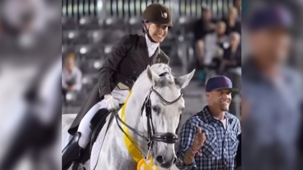 A woman smiles wide as she sits on her horse, Vanilla Ice. Rapper Vanilla Ice stands next to them, posing for a photo. He also smiles wide
