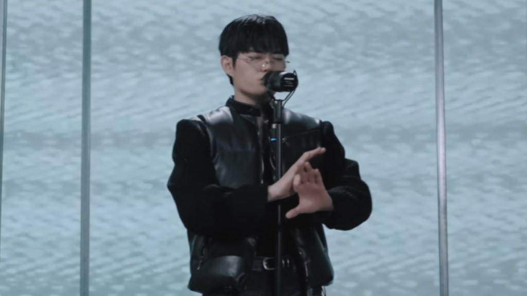 South Korean beatboxer, WING, closes his eyes as he performs in front of a mic. He has his hands out in front of him