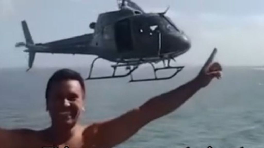Image shows a man during an epic photobomb by a police helicopter.
