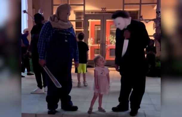 Image shows a little girl looking up at "Michael Myers" from "Halloween" with total adoration.
