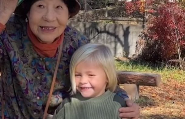 Image shows a Japanese woman posing for a picture with a young blond child that was visiting the country.