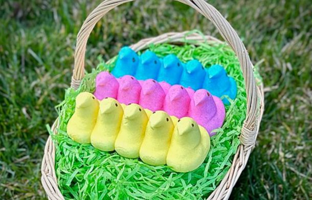 Image shows three rows of yellow, pink, and blue Peeps sitting on fake grass in an Easter basket.