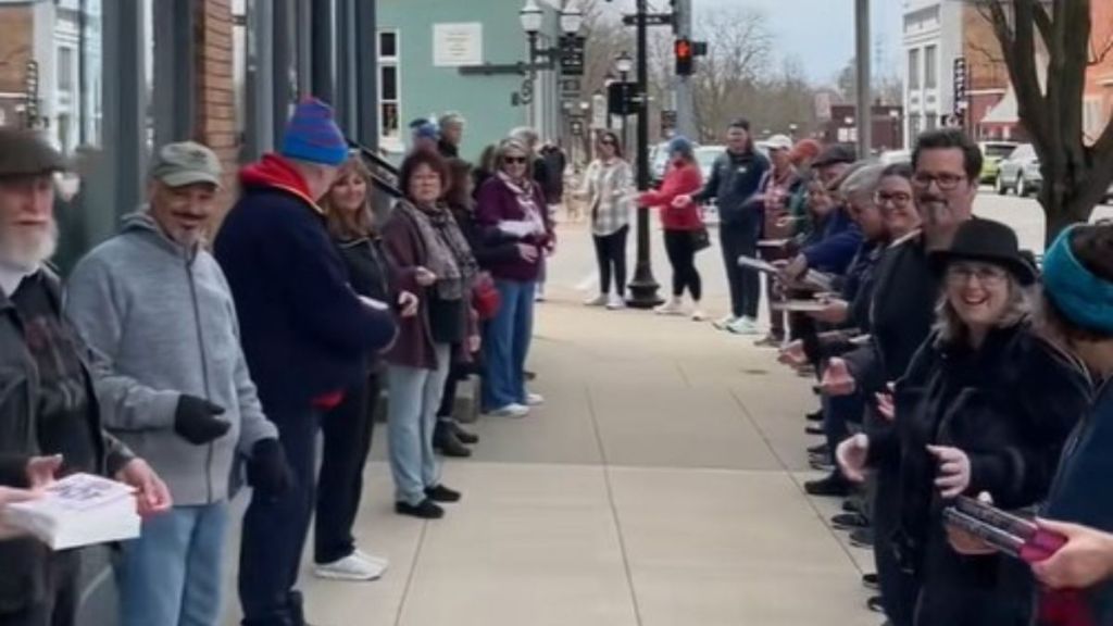 Image shows people lining a sidewalk on both sides passing books to move a local bookstore.