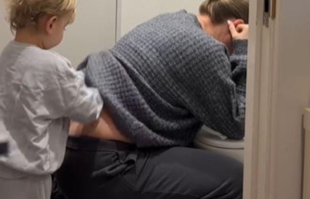 Image shows a toddler rubbing his mom's back to help her morning sickness.