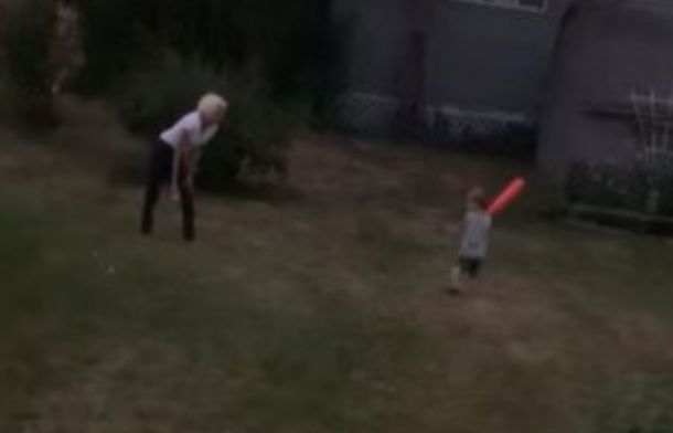 Image shows widowed neighbor playing whiffle ball with a young boy.