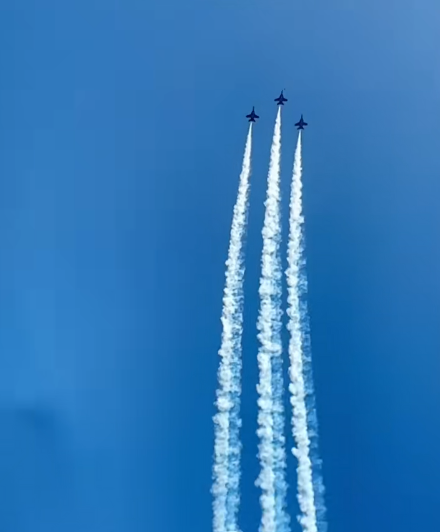 View of three Blue Angels planes flying side-by-side and straight up. The sky is a bright blue