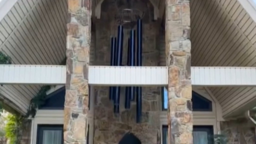 View of a front porch with large pillars. Hanging in the middle of the porch is a giant wind chime