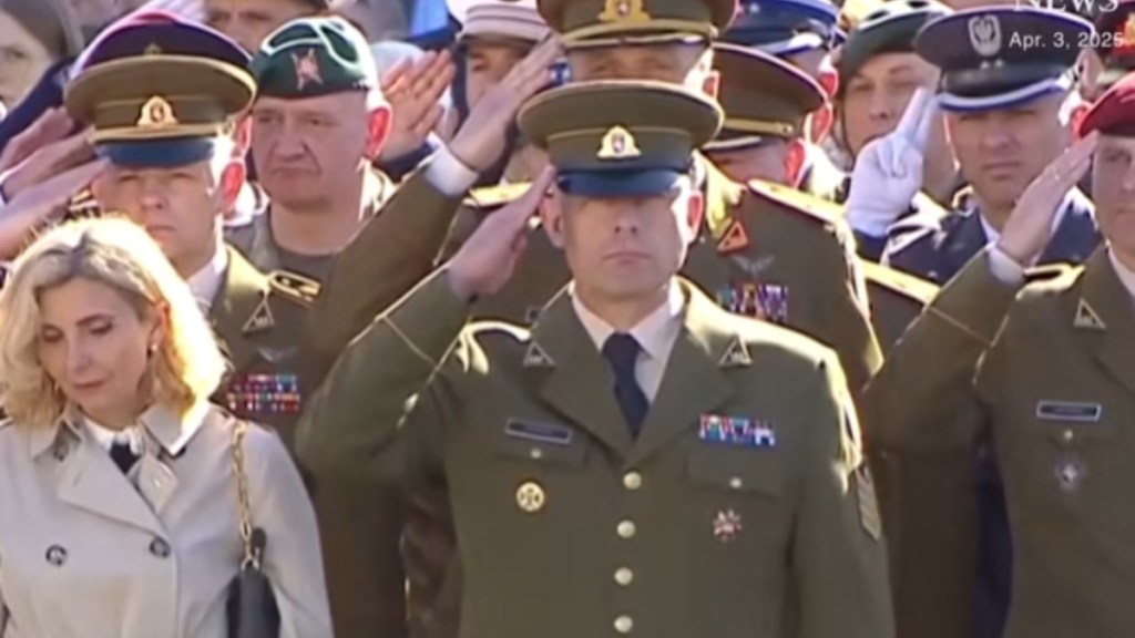 A number of Lithuanian soldiers solute as they stand closely in a group