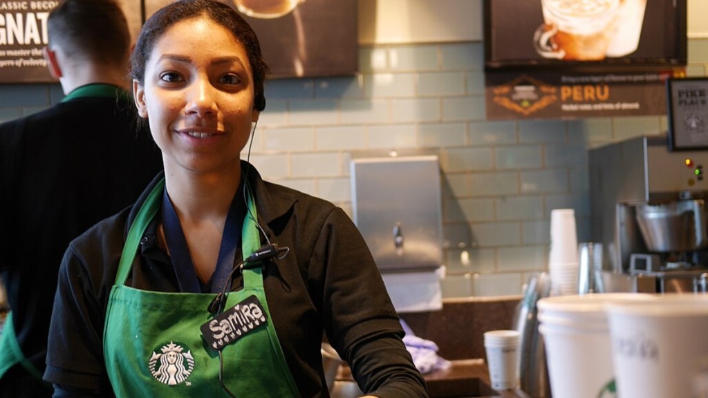 Close up of a Starbucks barista smiling. She's wearing a black button-up shirt and the Starbucks green apron