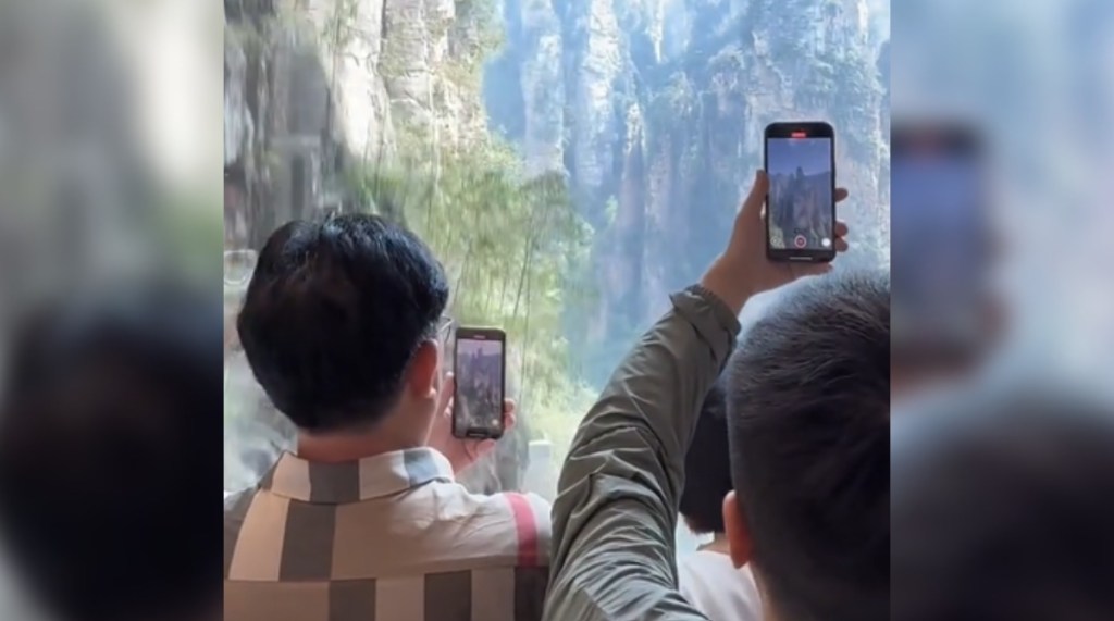 View of Zhangjiajie National Forest Park in Hunan, China as seen from the world's tallest and fastest outdoor elevator. People stand with their phones out, recording the view