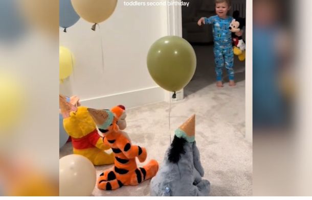 Toddler sees the Pooh friends waiting with birthday hats and balloons to celebrate his second birthday.
