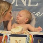 Image shows a Mom sharing a birthday cake with her one-year-old.