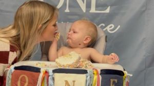 Image shows a Mom sharing a birthday cake with her one-year-old.