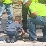 Concrete workers stop to show a young boy how to lay concrete.