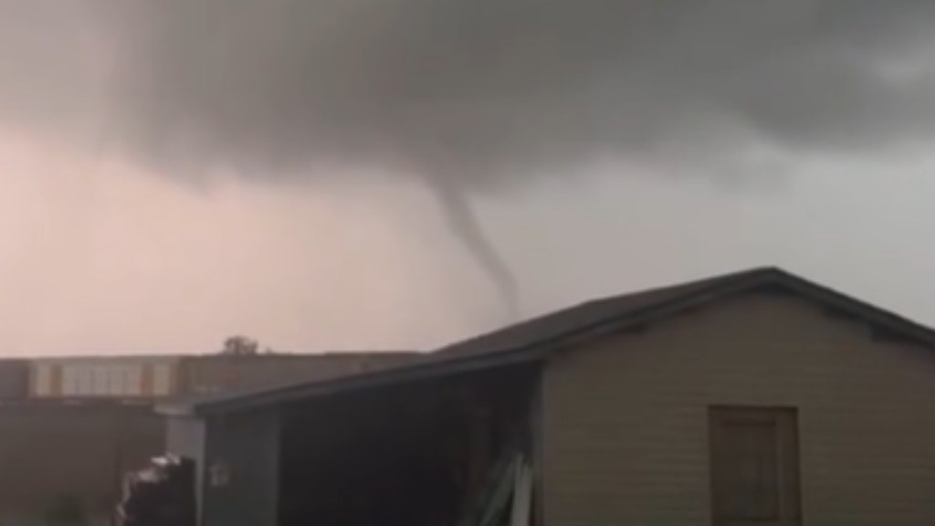 View from a distance of a thin tornado moving behind buildings