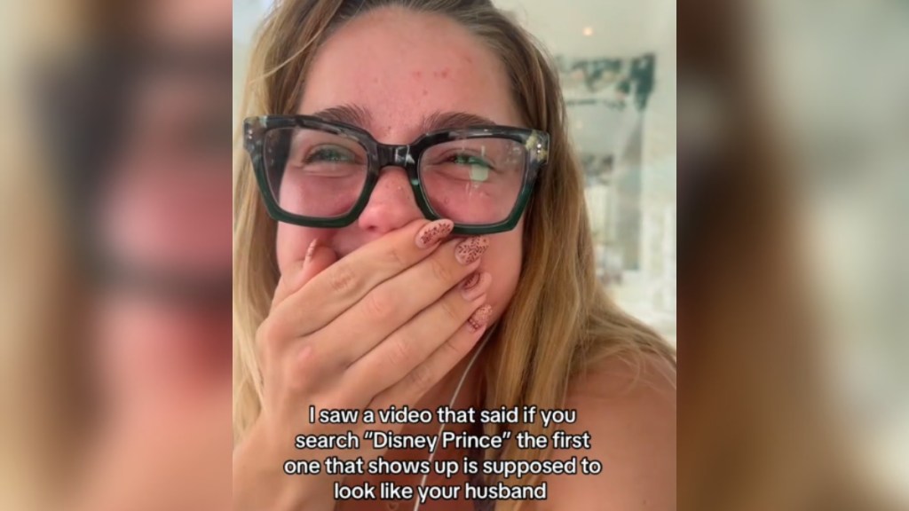 A woman looks happily surprised, covering her mouth with her hand. Text on the image reads: I saw a video that said if you search "Disney Prince" the first one that shows up is supposed to look like your husband