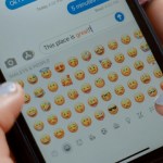 Close up of someone texting on an iPhone. The person texting is viewing emoji options