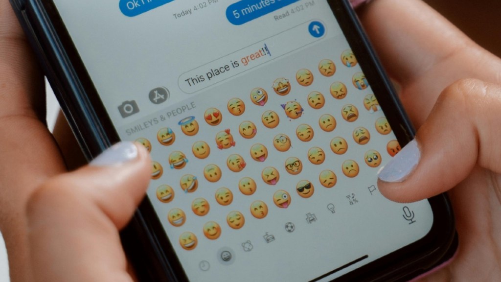 Close up of someone texting on an iPhone. The person texting is viewing emoji options