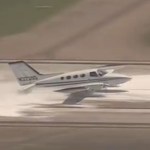 A small plane lands without a landing gear. Foam is in the runway