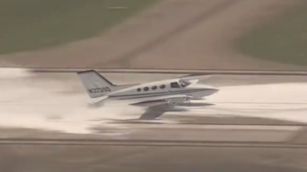 A small plane lands without a landing gear. Foam is in the runway