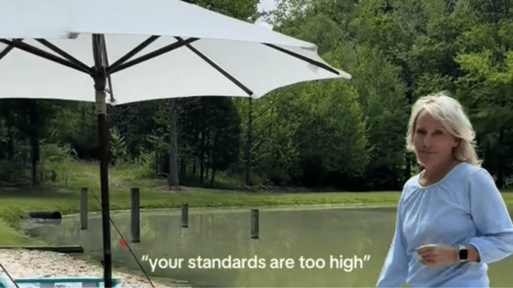 a woman standing near a white umbrella with a pond in the background