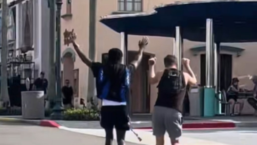 View from behind of two men dancing as they walk down the street of Universal Studios