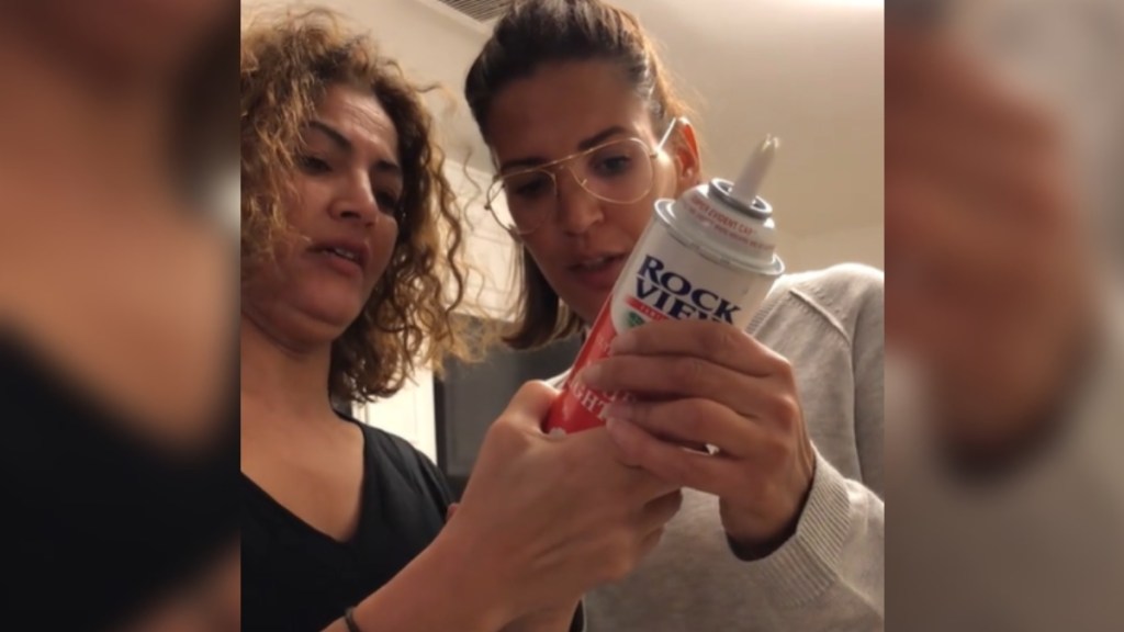 Two women hold onto a can of whipped cream. They're concentrating as they read the instructions.